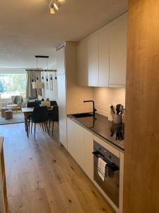 a kitchen with white cabinets and a dining room at Calarosa Boutique Apartment Arosa in Arosa
