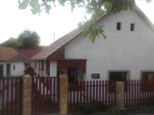 a white house with a wooden fence and a building at Bekecs Vendégház in Nagyvisnyó