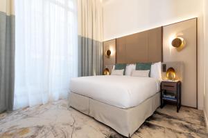 ein Schlafzimmer mit einem großen weißen Bett und einem Fenster in der Unterkunft InterContinental Paris Champs Elysées Etoile, an IHG Hotel in Paris
