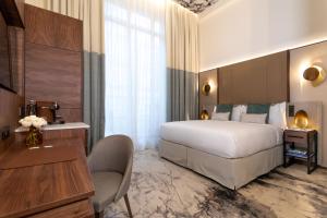ein Hotelzimmer mit einem großen Bett und einem Schreibtisch in der Unterkunft InterContinental Paris Champs Elysées Etoile, an IHG Hotel in Paris