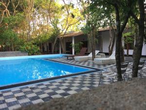 una casa y una piscina con suelo a cuadros y sillas en AliKele Hotel & Resort, en Sigiriya