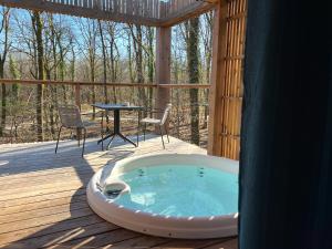 un bain à remous sur une terrasse avec une table dans l'établissement Loire Valley Lodges - Hotel, à Esvres