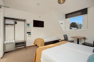 a hotel room with two beds and a television at Hotel de Logerij Renesse in Renesse
