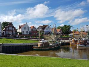 a group of boats docked in a river with houses at Hotel Greetsiel in Greetsiel