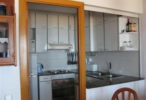 uma cozinha com armários brancos, um lavatório e um fogão em Baywatch Penthouse em Altafulla
