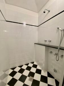 a bathroom with a shower and a checkered floor at CASA HERMES in Bergamo