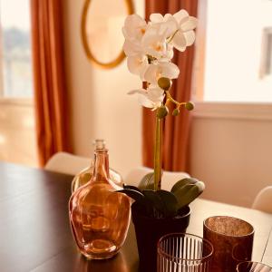 eine Glasflasche und eine Vase mit Blumen auf dem Tisch in der Unterkunft L'Ekrin des Cimes in Le Mont-Dore