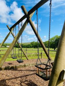 three swings in a playground with a field in the background at Canllefaes Cottages in Cardigan