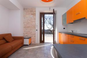 a kitchen with orange cabinets and a couch in a room at A03 - Massignano, bilocale immerso nel verde 1 in Ancona