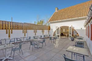 a patio area with tables, chairs and umbrellas at Hotel de Logerij Renesse in Renesse