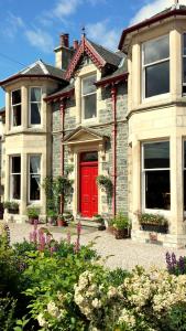 a red door on a house with a garden at Strathallan Bed and Breakfast in Grantown on Spey