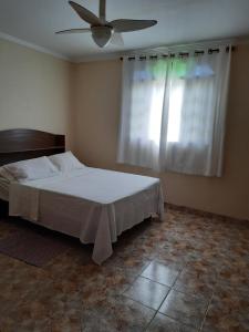 1 dormitorio con 1 cama y ventilador de techo en Casadateca en Praia Vermelha
