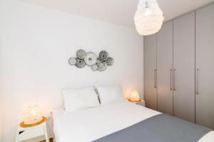 a white bedroom with a bed and a clock on the wall at IKIES TINOS A and B in Tinos