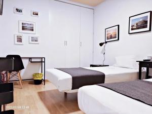 a hotel room with two beds and a desk at Habitaciones con encanto junto al Mercado Central in Valencia