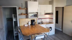 a small kitchen with white cabinets and a wooden table at Studio spacieux proche plage. Wi-fi, climatisation in Bormes-les-Mimosas