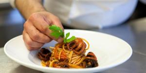 a person holding a plate of spaghetti with a garnish at Pigna Felice Punta Ala in Punta Ala