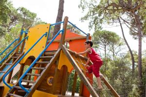 a young boy is climbing up the stairs of a playground at Pigna Felice Punta Ala in Punta Ala