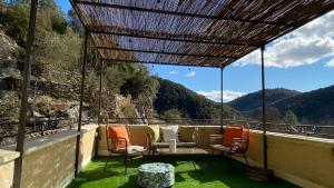 a patio with a couch and chairs on a balcony at Maison au cœur des Cévennes Méridionales in Saint-André-de-Majencoules