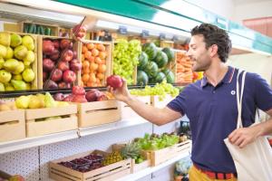 a man is holding a apple in a grocery store at Pigna Felice Punta Ala in Punta Ala