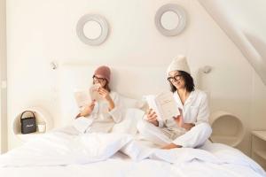 a man and woman sitting in bed reading books at Hôtel de Banville in Paris