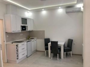 a kitchen with white cabinets and a table and chairs at Apartman Silver Star in Sombor