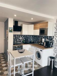 a kitchen with a table and a washing machine at NEW: appartement tout confort + parking gratuit in Amiens