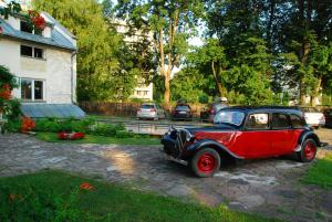 an old red car parked in front of a house at Drusva Apartamentai in Druskininkai
