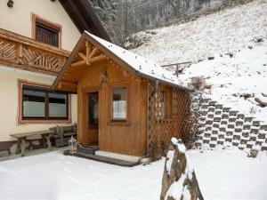 una cabaña de madera en la nieve con un banco en Cosy holiday home in a charming area en Muhr