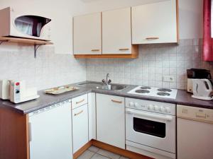 cocina con armarios blancos, fogones y fregadero en Apartment near the ski area in Sautens, en Sautens