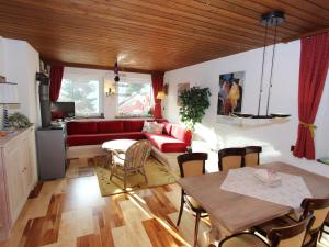 a living room with a red couch and a table at Charming Chalet in Niedernsill near Ski Area in Niedernsill