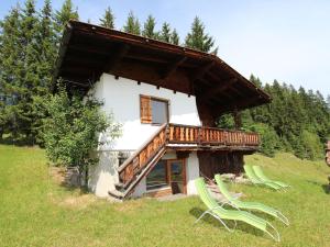une maison avec une terrasse et deux chaises dans un champ dans l'établissement Chalet in Hopfgarten Brixental in ski area, à Hopfgarten im Brixental