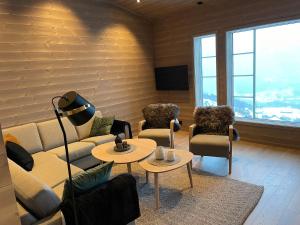 una sala de estar con sofás, mesas y ventanas en Panorama 17 - fantastisk utsikt! en Sogndal