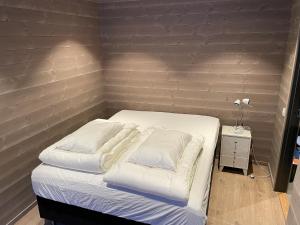 a bed with white sheets and pillows in a room at Panorama 17 - fantastisk utsikt! in Sogndal