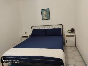 1 dormitorio con 1 cama azul y blanca y 2 mesas en casetta, en Isquia