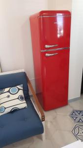 um frigorífico vermelho num quarto com uma cadeira azul em casetta em Ischia