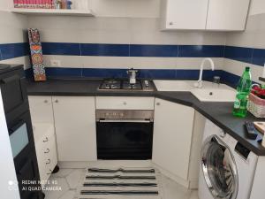 uma cozinha com um lavatório, um fogão e uma máquina de lavar louça em casetta em Ischia