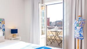 a bedroom with a bed and a balcony with a table at Praça 44 Boutique Apartments in Braga
