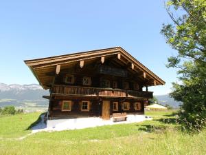 a large wooden house on a hill with mountains in the background at Chalet on the ski slope in St Johann in Tyrol in Apfeldorf