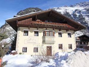 una casa en la nieve con montañas en el fondo en Quaint Apartment in L ngenfeld with Sauna en Huben
