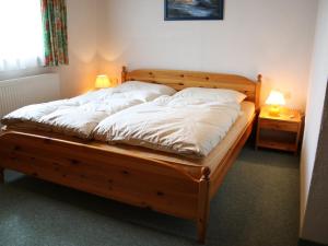 ein Schlafzimmer mit einem Holzbett mit weißer Bettwäsche und zwei Lampen in der Unterkunft Spacious Chalet in Flachau with Sauna in Flachau