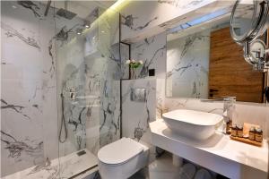a bathroom with a toilet and a sink and a shower at Emily's Luxury Suites in Pefkochori