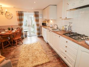 a kitchen with white cabinets and a table with a dining room at Bridge End Bothy in Wooler