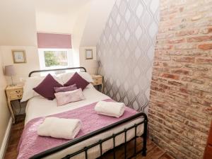 a bed in a room with a brick wall at Bridge End Bothy in Wooler