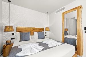 a bedroom with a bed with white sheets and a mirror at Emily's Luxury Suites in Pefkochori