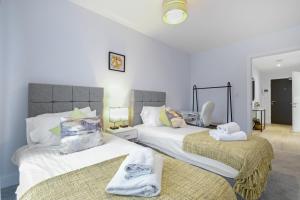 - une chambre avec 2 lits et des serviettes dans l'établissement Belmore 1 & 2 Bedroom Luxury Apartments with Parking in Stanmore, North West By 360 Stays London, à Stanmore