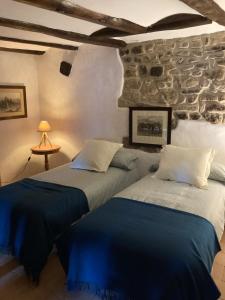 2 camas en una habitación con una pared de piedra en La Casa del Bosque, en Cabra de Mora