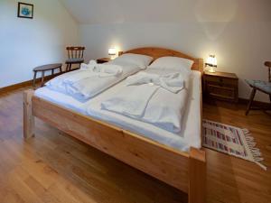 Elle comprend un grand lit en bois avec des draps et des oreillers blancs. dans l'établissement Apartment in Mooswald in Carinthia with pool, à Fresach