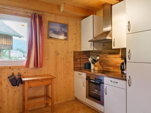a kitchen with white appliances and a wooden wall at Chalet in Sankt Georgen near ski area in Sankt Georgen ob Murau