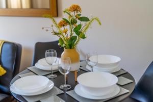 a table with plates and glasses and a vase with flowers at Pierocks Wickets Luxury Entire house, Free Parking and WI-FI in Maidenhead in Maidenhead