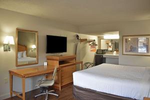 Rodeway Inn Hot Springs National Park Area في هوت سبرنغز: غرفة فندقية فيها سرير ومكتب وتلفزيون